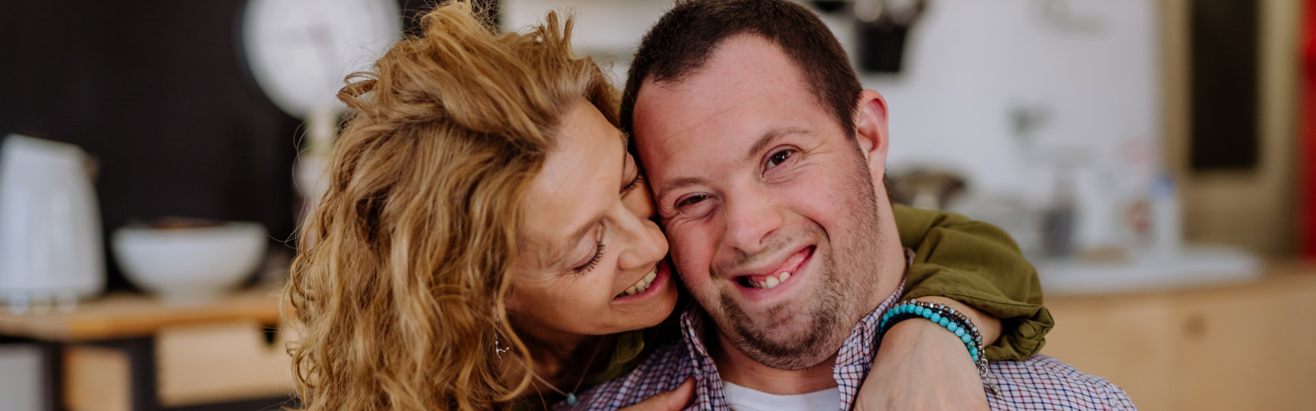 A portrait of mother hugging her grown up son with Down syndrome