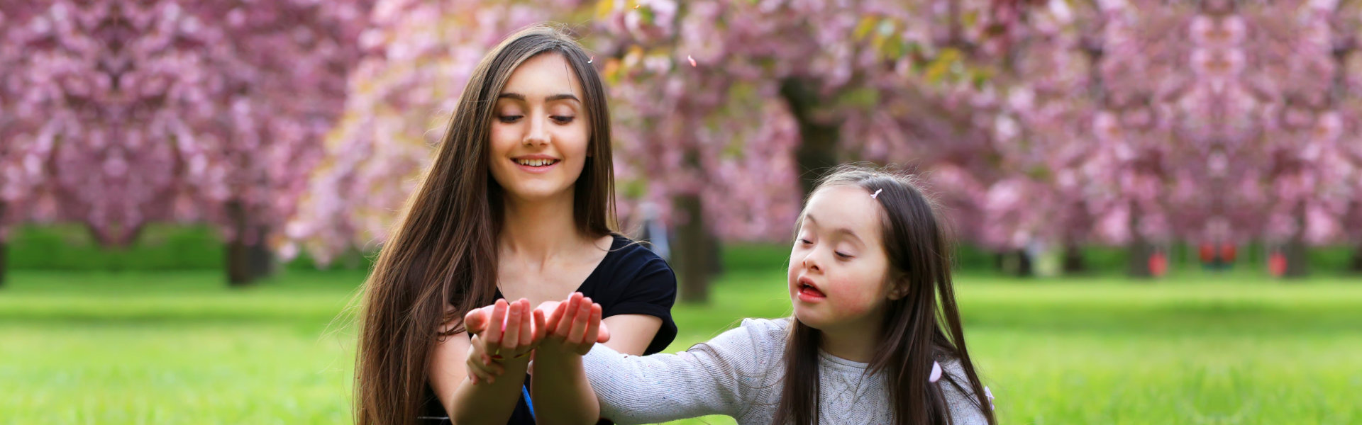 Happy beautiful young women with girl in blossom park with trees and flowers